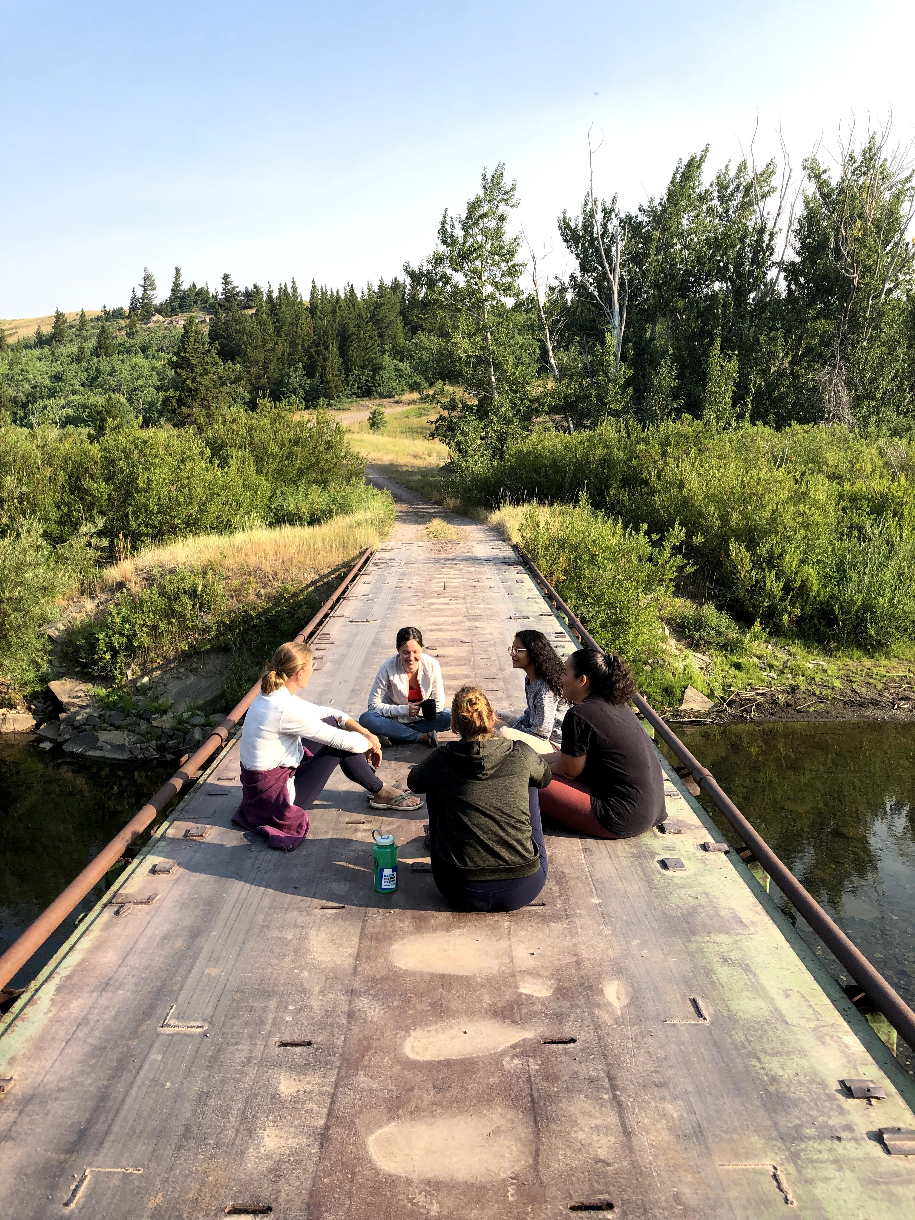 A group of 5 women sit on a bridge in Montana.